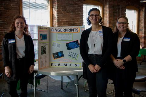 Three women standing in from of poster that says "fingerprints"