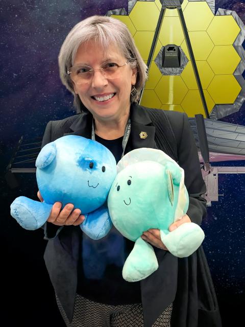 Woman holding two stuffed animals that represent planets