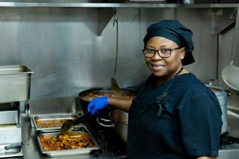 kitchen worker stirring food and smiling