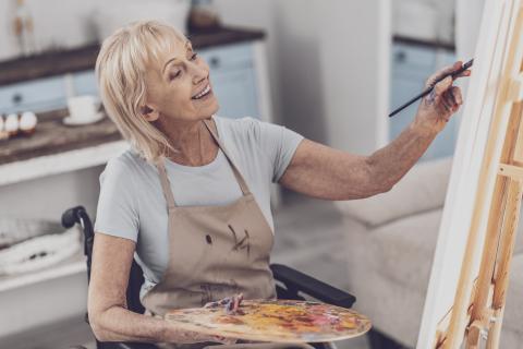 Joyful process. Creative disabled woman feeling extremely happy enjoying the process of drawing portrait.