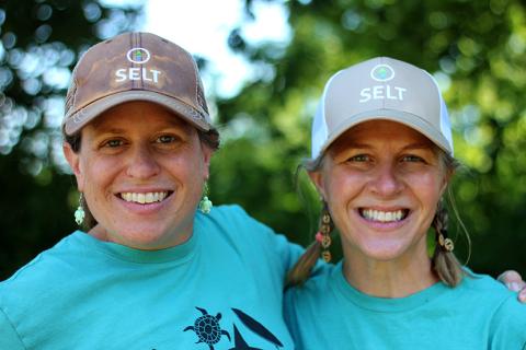 Two adult camp counselors posing outside