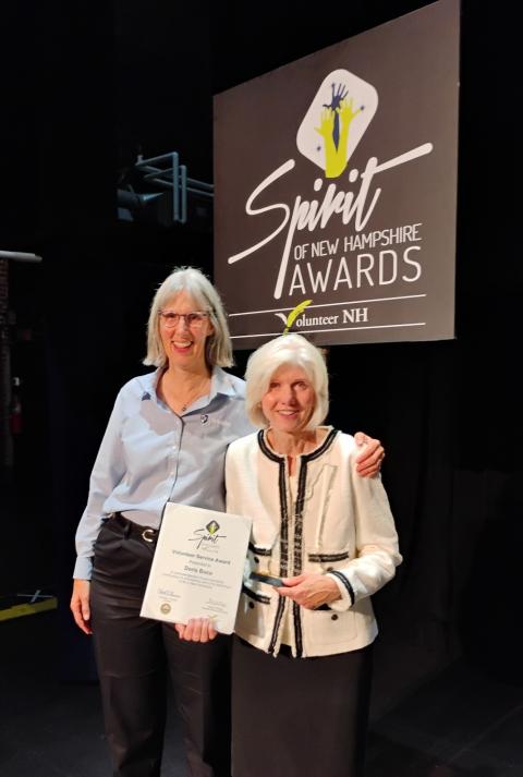 Two women standing on stag with an award