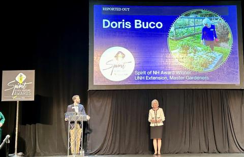 Woman standing on stage for an award with a presenter at podium