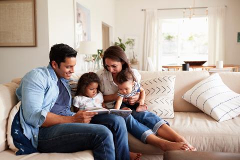 Family sitting on couch, looking at tablet