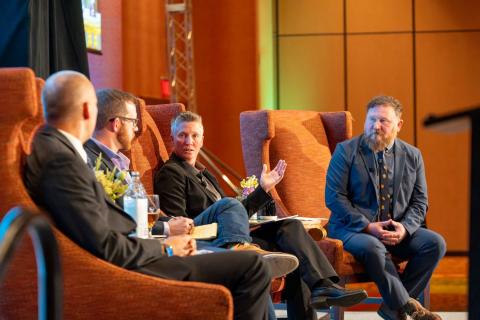 Four people sitting on a stage, talking