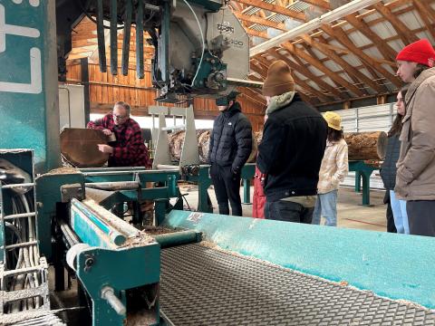 participants standing by a machine in a sawmill