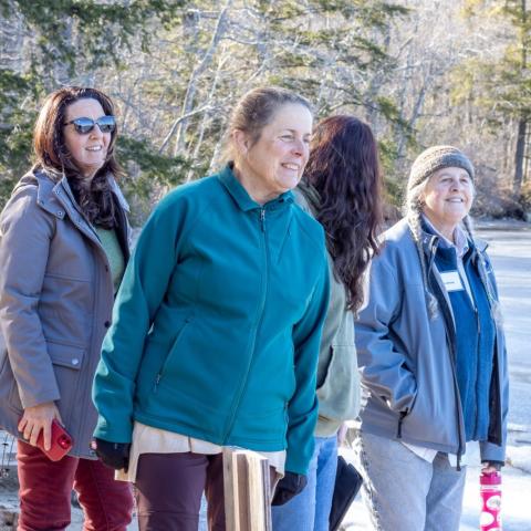 three women smiling while standing outside