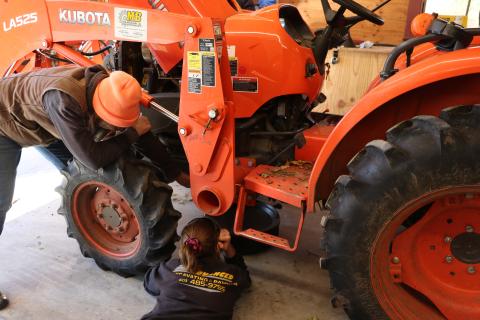 Two women working on a tractor