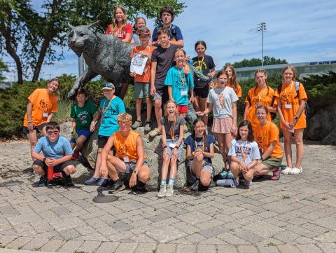 Kids from Camp Atlas standing around the UNH Wildcat on Durham campus