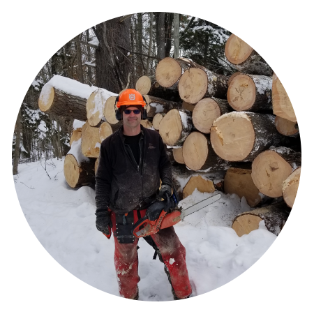 jim frohn standing in the snow by a pile of timber