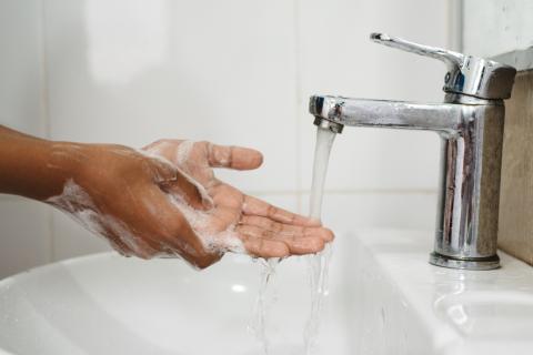 person washing hands with soap and water over a sink