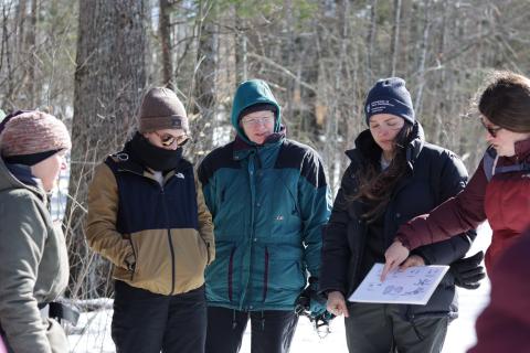 a group of women look at wildlife tracks on a piece of paper