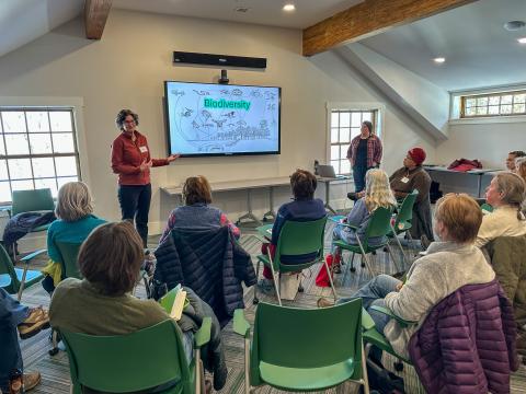 a group of women watching a presentation about wildlife and the slide on the screen says biodiversity