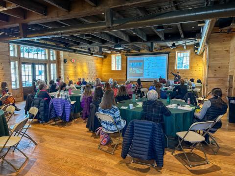 a large group of women watch a presentation about trail design