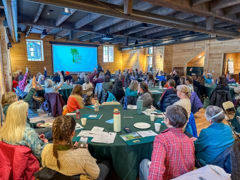 a group of seventy women gathered inside watching a presentation