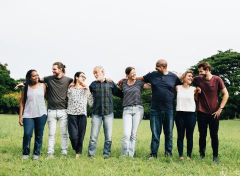 Group of people with arms around each other in a park.
