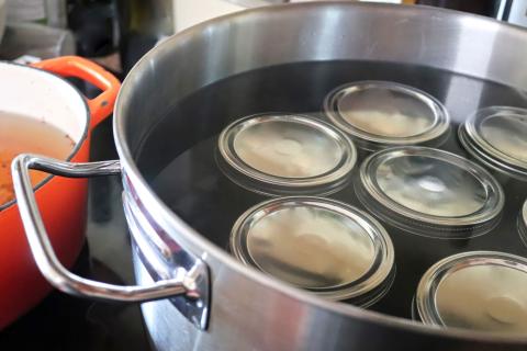 stainless steel pot containing canning jars and water for boiling water processing