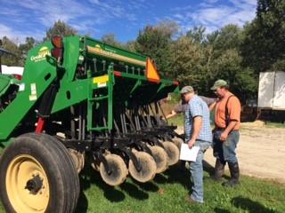 two men looking at a no-till seed drill