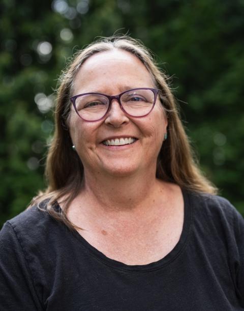 Ann Hamilton wearing purple glasses and dark shirt with trees in the background