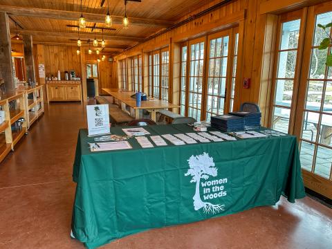 Green tablecloth with women in the woods logo. Registration table setup.