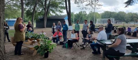 Woman teaching a group outside in wooded area