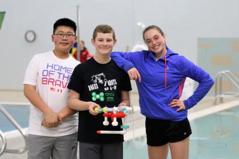 Students pose with their underwater drone at the pool