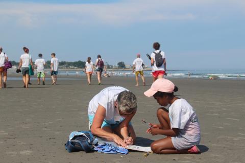 A citizen scientist volunteer works with a youth at the Beach Blitz event.