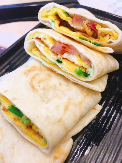 Breakfast burrito with eggs, ham, and green onions.
