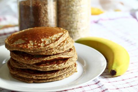 Stack of whole wheat pancakes with a whole unpeeled banana.