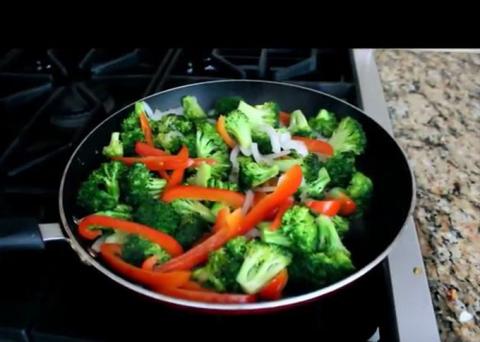 Skillet with broccoli, red pepper strips and chopped onion.