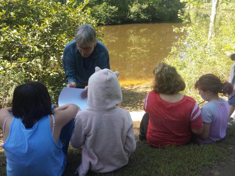 STEM Docent volunteer Emily Wrubel teaching children in front of a stream