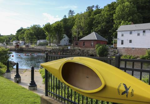 A kayak mounted on a fence in a park in Franklin NH. A river is in the background.