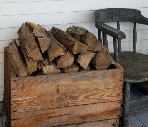 wood pile in wood box beside wooden chair
