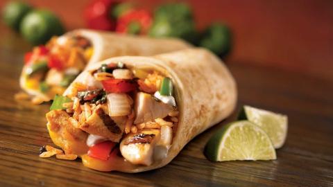Chicken fajitas wrap filled with chicken and vegetables. With lime wedges on the side.