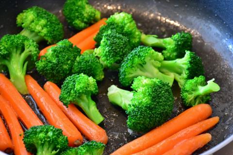 Skillet with broccoli and carrots being stir fried.