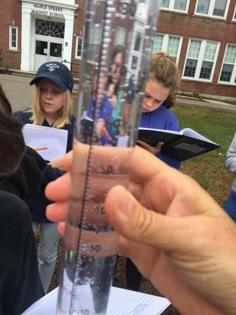 students looking at rain gauge