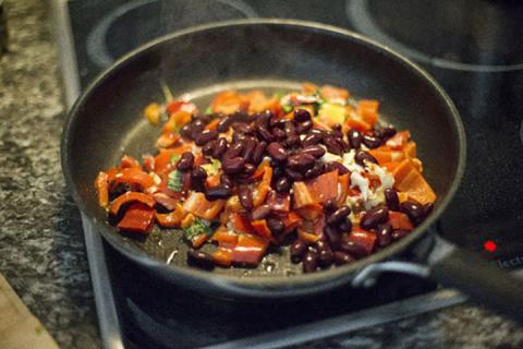 Skillet on stove top with chopped peppers, onion and kidney beans.