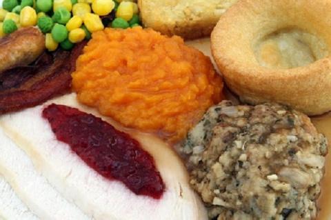 A plate of roast turkey. mashed portatoes, yams, corn and peas