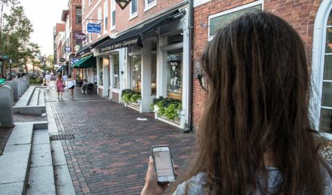 Close-up of a person on a sidewalk using the First Impressions app to provide feedback about a community.