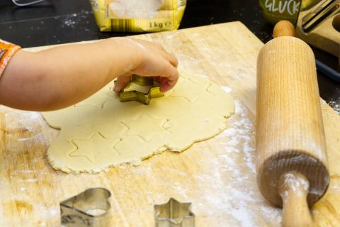 Child cutting cookie dough with hands.