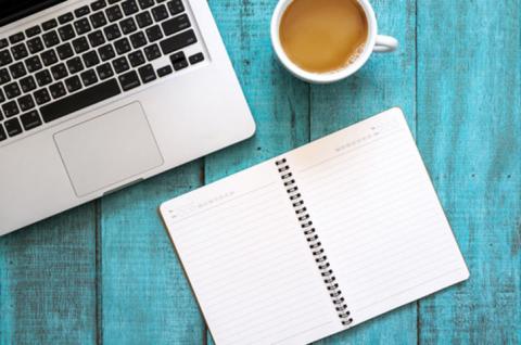blue desktop with notepad and laptop