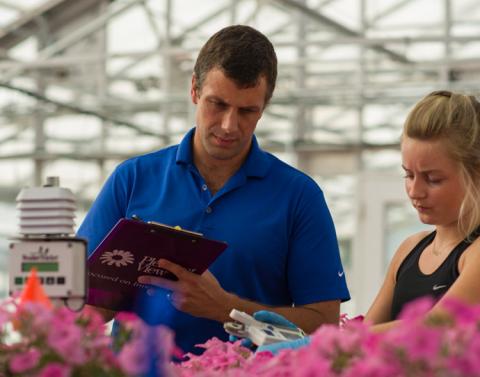 Extension specialist Ryan Dickson and a UNH intern work with plants in a greenhouse.
