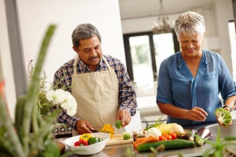 Older couple washing and chopping fresh vegetables.