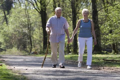 two older adults walking along a park path