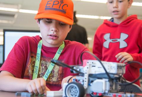 Boy wearing orange EPIC hat, working on a robot car