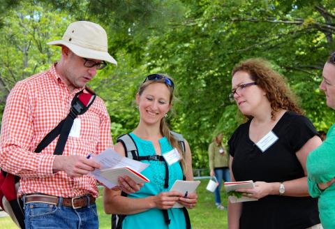 Four teachers collaborate outside in front of trees