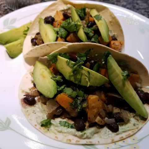 Plate with bean tacos topped with avocado slices.