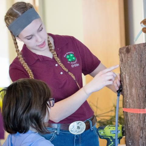 4-H volunteer showing child how to measure tree