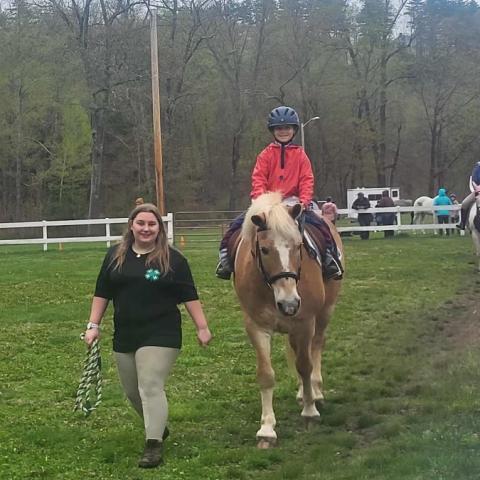Memeber helping a cloverbud member ride a horse at horse clinic.