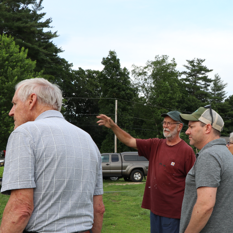 Three older men talking in a field